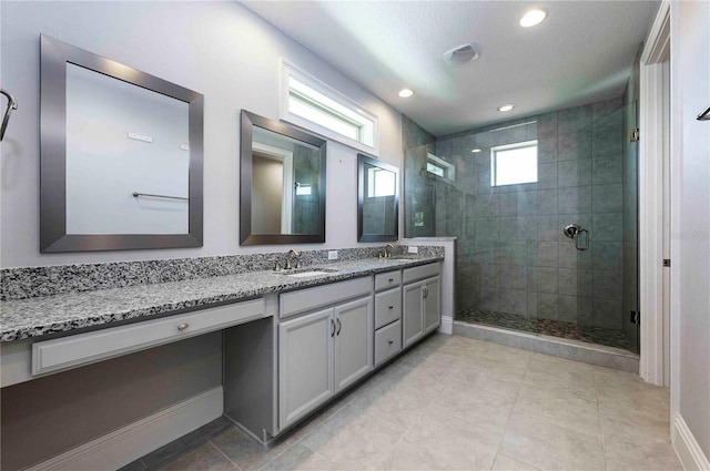 bathroom featuring baseboards, double vanity, a sink, and a shower stall