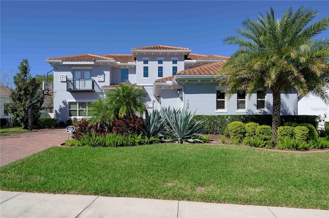 mediterranean / spanish-style home featuring a tile roof, a front yard, and stucco siding