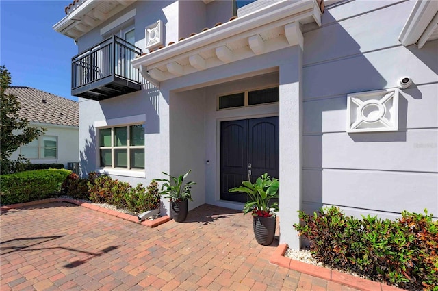 property entrance featuring a balcony and stucco siding