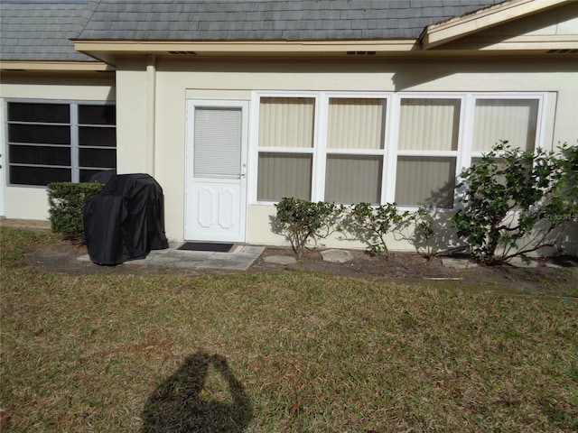 entrance to property with a lawn and stucco siding