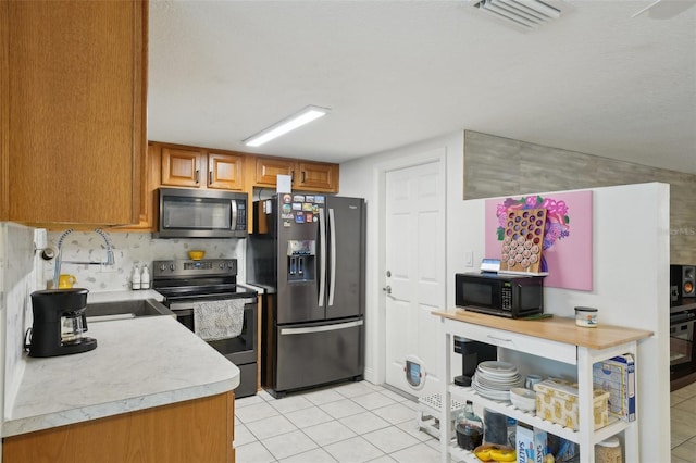 7740 Bracken Dr, Port Richey, FL 34668 - kitchen with visible vents, decorative backsplash, brown cabinets, light countertops, and black appliances