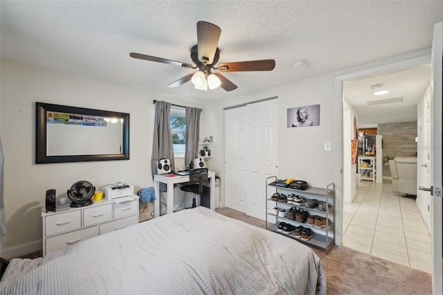 7740 Bracken Dr, Port Richey, FL 34668 - bedroom featuring light tile patterned floors, a closet, light colored carpet, a ceiling fan, and a textured ceiling