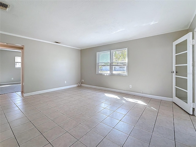 empty room with light tile patterned floors, ornamental molding, visible vents, and baseboards