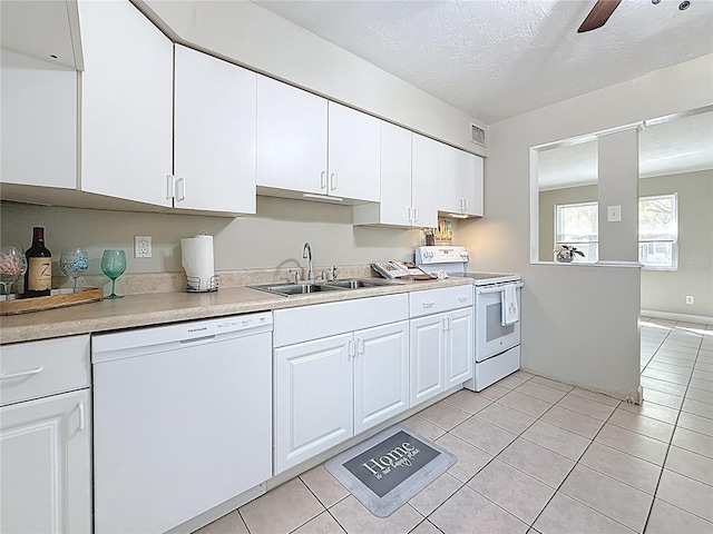 kitchen featuring white appliances, visible vents, white cabinets, light countertops, and a sink