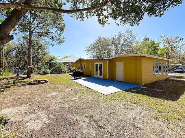 rear view of house with a fire pit, french doors, and a patio area