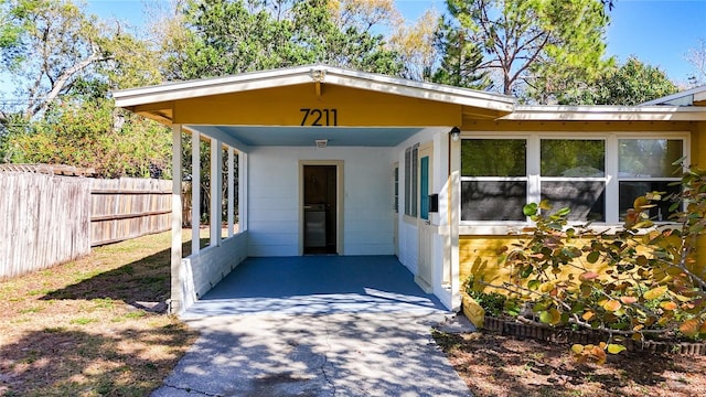 entrance to property featuring driveway, fence, and a carport