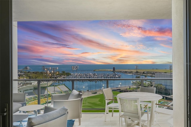 balcony at dusk featuring a water view