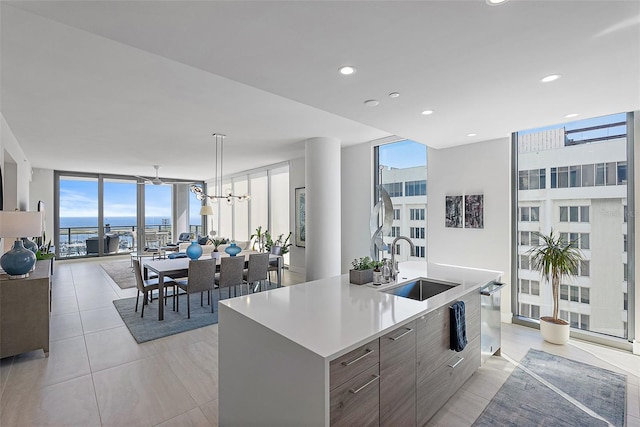 kitchen with an island with sink, modern cabinets, a sink, expansive windows, and a wealth of natural light