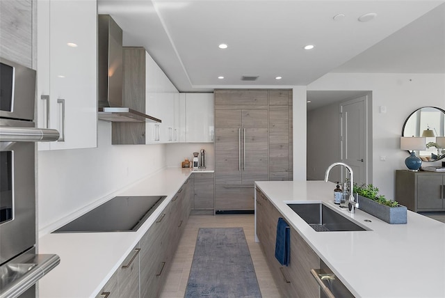 kitchen with black electric cooktop, a sink, wall chimney exhaust hood, and modern cabinets