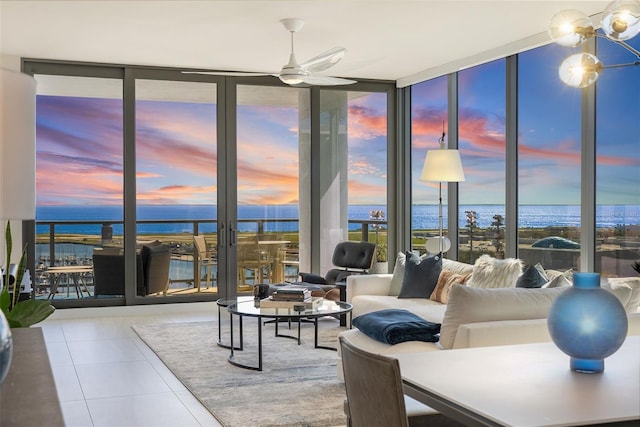 tiled living area featuring a ceiling fan, a wealth of natural light, floor to ceiling windows, and a water view