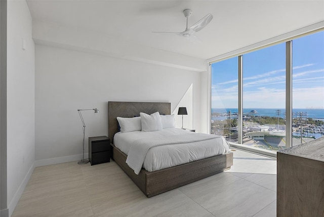 bedroom with baseboards, a ceiling fan, a water view, access to exterior, and floor to ceiling windows