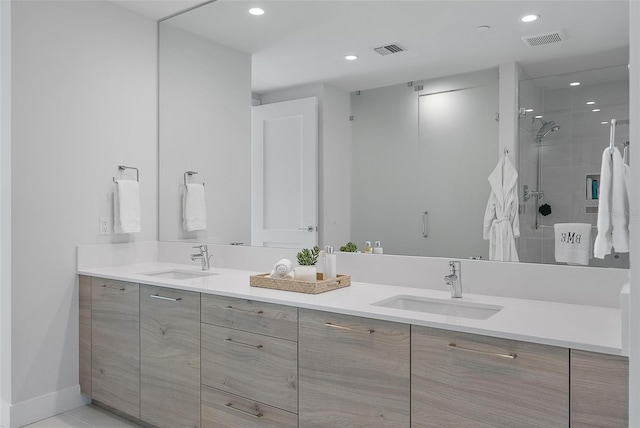 bathroom with double vanity, visible vents, a sink, and tiled shower