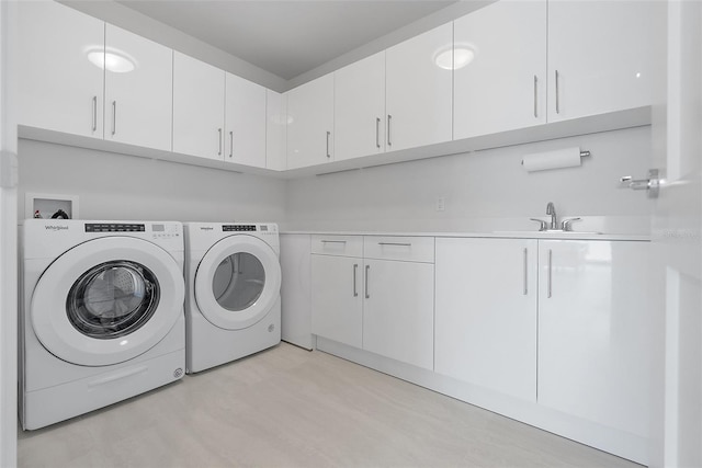 laundry room featuring cabinet space, separate washer and dryer, and a sink