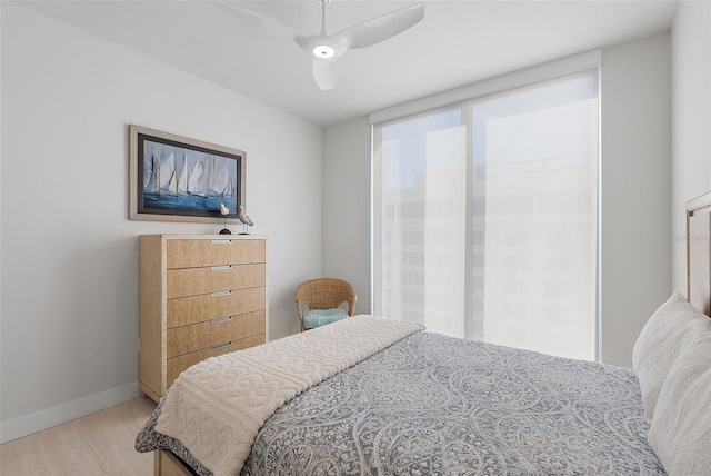 bedroom with light wood finished floors, a ceiling fan, and baseboards