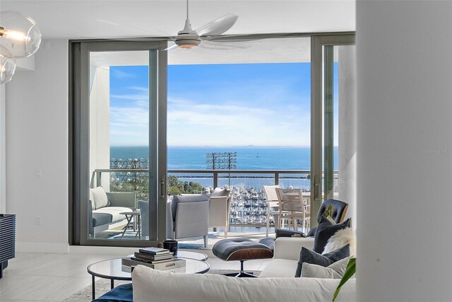 tiled living room with expansive windows, a water view, a ceiling fan, and a healthy amount of sunlight