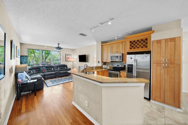 kitchen featuring visible vents, a peninsula, stainless steel appliances, a textured ceiling, and a sink