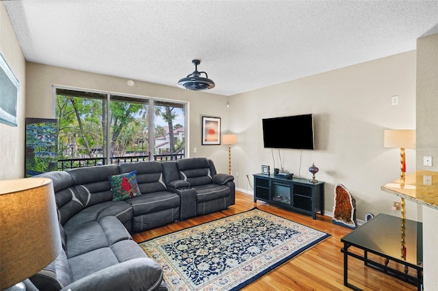 living area with a textured ceiling, baseboards, and wood finished floors