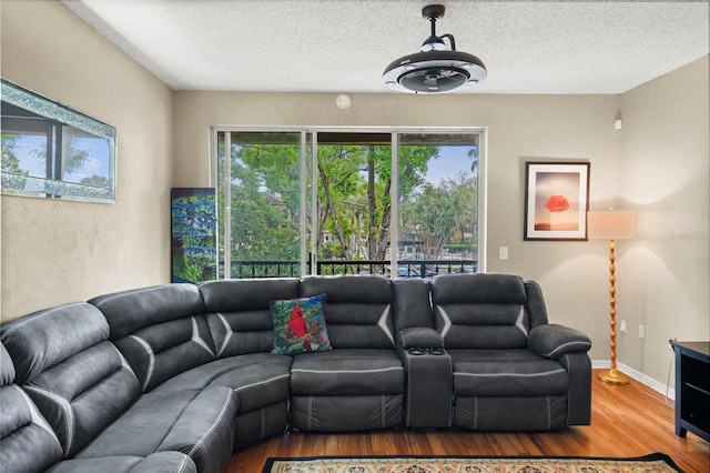 living area featuring a textured ceiling, baseboards, and wood finished floors