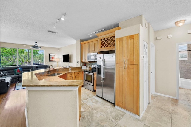 kitchen with visible vents, appliances with stainless steel finishes, open floor plan, a peninsula, and a sink