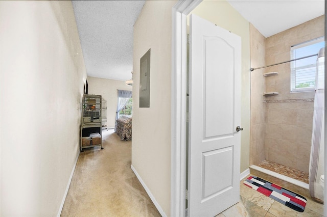 hall featuring baseboards, a textured ceiling, and carpet flooring