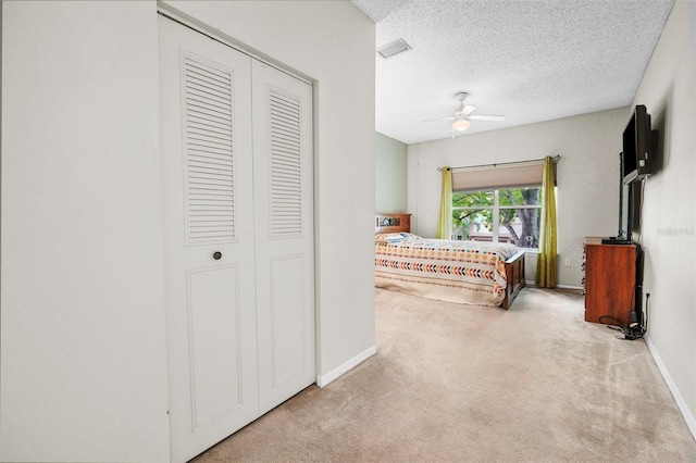 carpeted bedroom featuring a ceiling fan, a closet, a textured ceiling, and baseboards