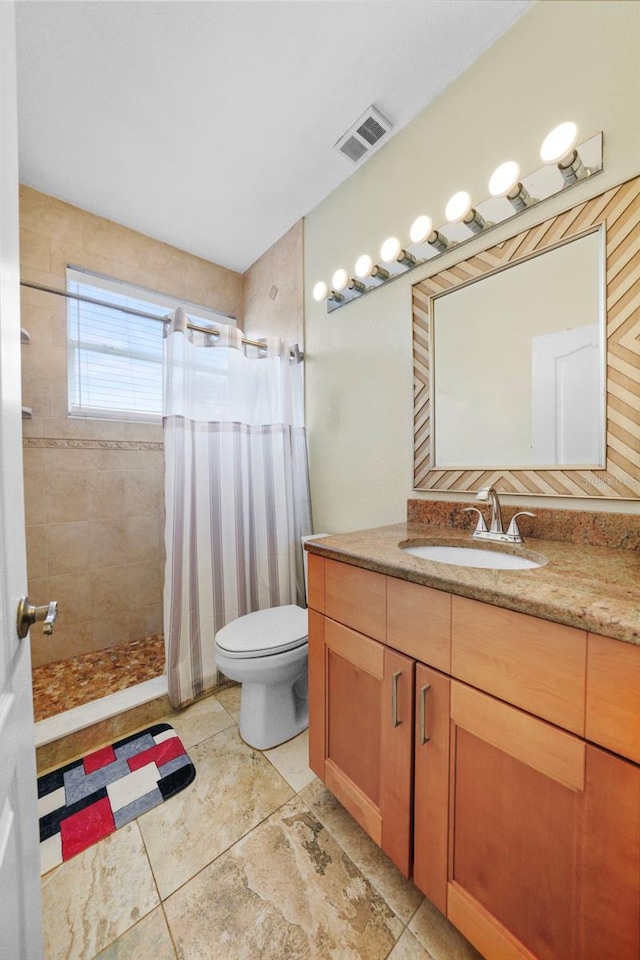 full bath featuring toilet, vanity, a tile shower, and visible vents