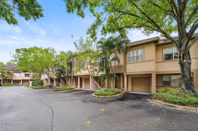 view of property featuring driveway, an attached garage, and stucco siding