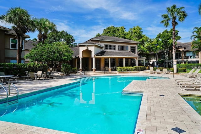 pool with a patio area and fence