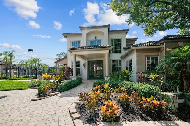 back of house featuring a tiled roof, french doors, fence, and stucco siding