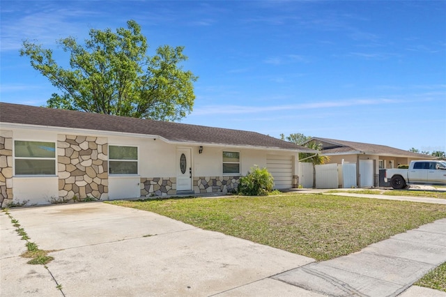 single story home featuring stucco siding, stone siding, a front yard, and fence