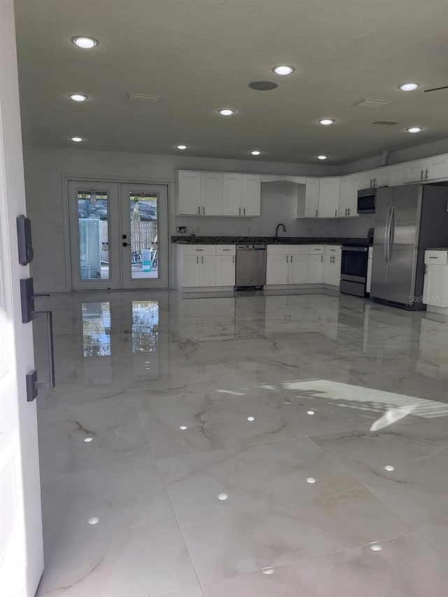 kitchen with recessed lighting, stainless steel appliances, dark countertops, and white cabinetry