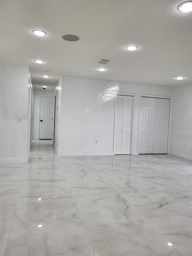 empty room featuring baseboards, visible vents, recessed lighting, a textured ceiling, and marble finish floor