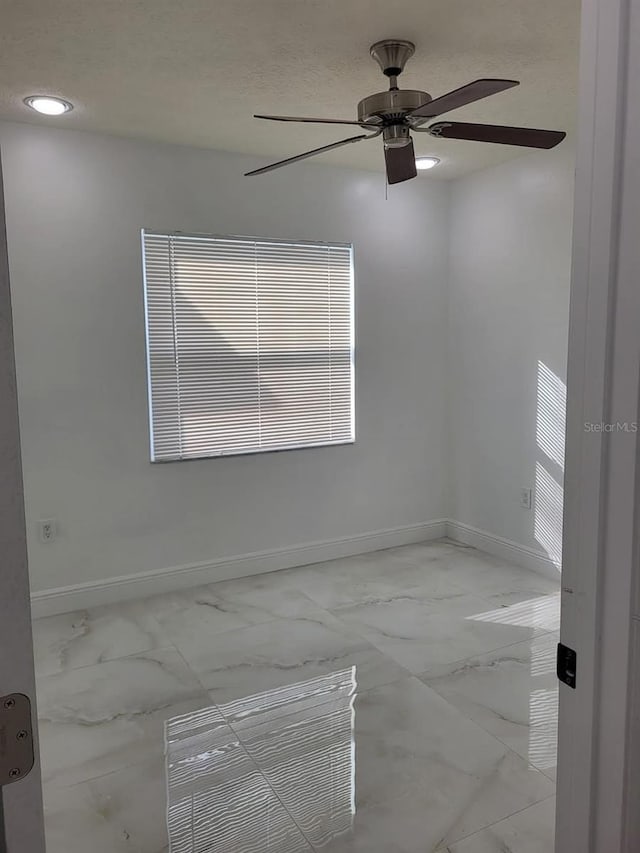 unfurnished room featuring baseboards, marble finish floor, and a ceiling fan