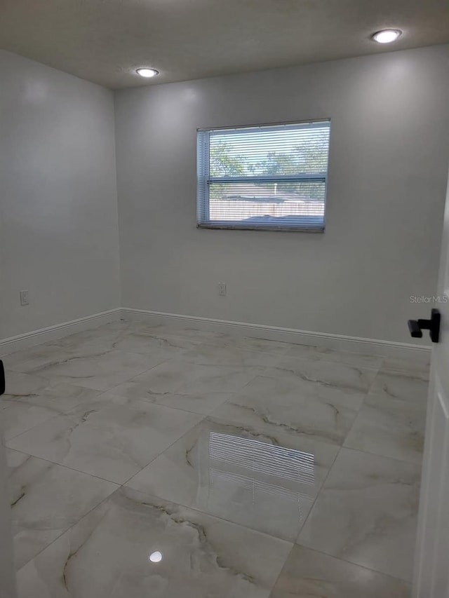 unfurnished room featuring recessed lighting, baseboards, and marble finish floor