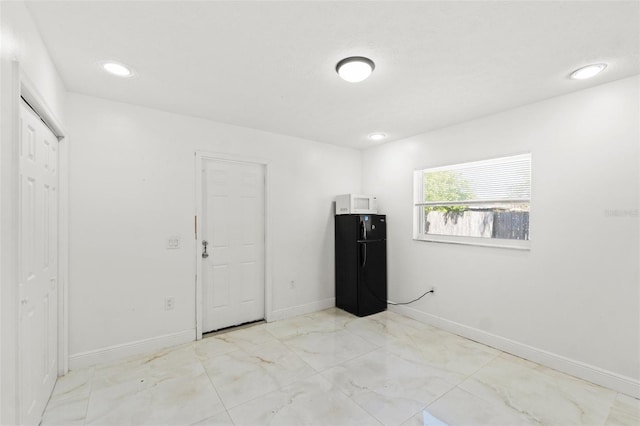 unfurnished bedroom featuring marble finish floor, recessed lighting, freestanding refrigerator, and baseboards