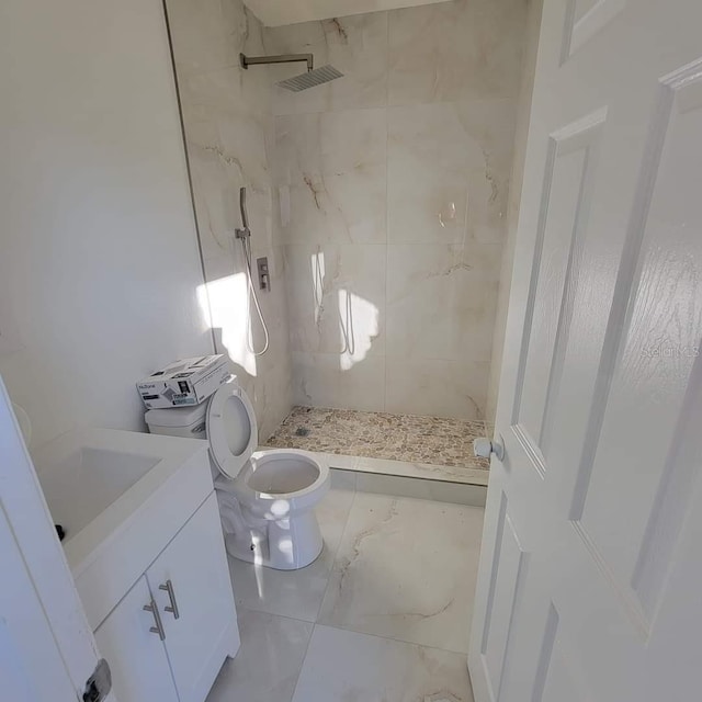 bathroom with marble finish floor, a stall shower, toilet, and vanity