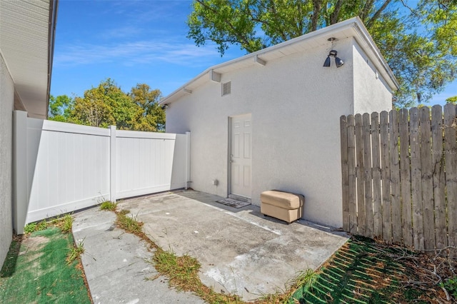 view of side of home featuring a patio area, fence, and stucco siding