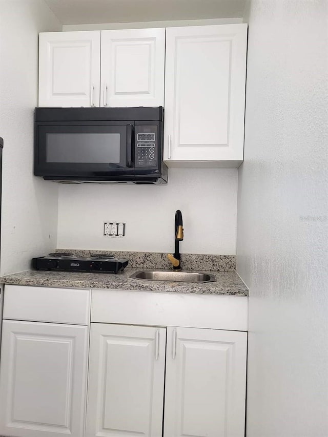 bar with black microwave and a sink