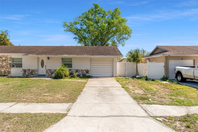 ranch-style home featuring concrete driveway, stucco siding, stone siding, an attached garage, and a gate