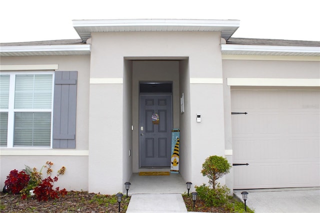 entrance to property featuring a garage and stucco siding