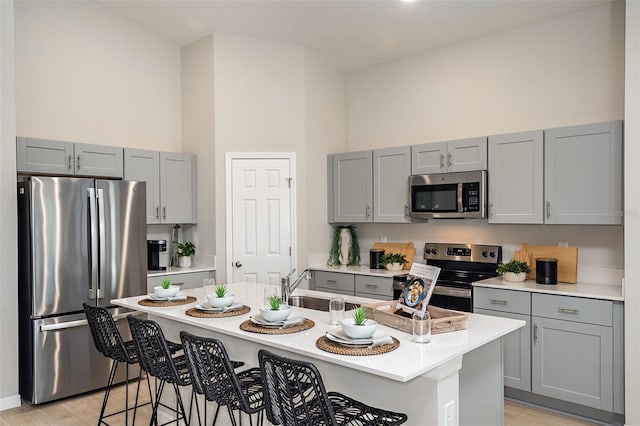 kitchen with appliances with stainless steel finishes, a breakfast bar area, and gray cabinetry