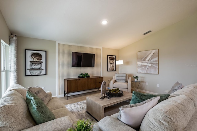 living room featuring vaulted ceiling, wood finished floors, visible vents, and baseboards