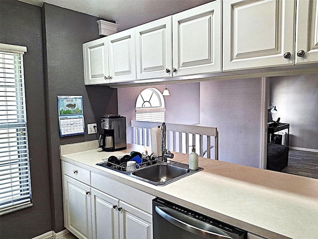 kitchen with a sink, white cabinetry, light countertops, and dishwasher