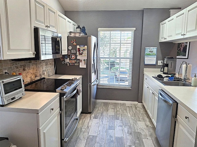 kitchen featuring a toaster, a sink, appliances with stainless steel finishes, backsplash, and light wood finished floors