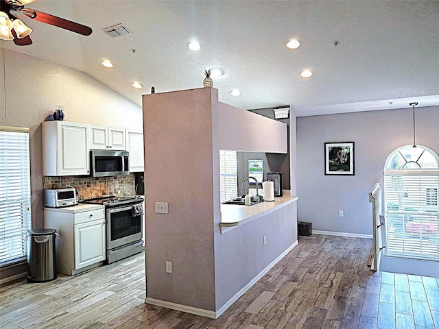 kitchen featuring stainless steel appliances, visible vents, backsplash, wood tiled floor, and white cabinetry