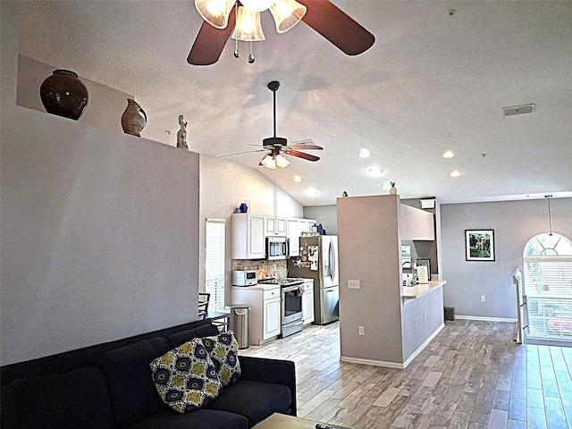 living room featuring lofted ceiling, light wood-style flooring, a ceiling fan, visible vents, and baseboards