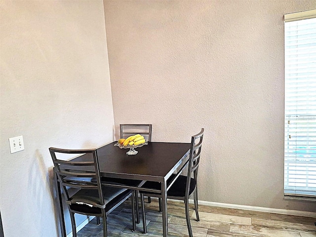 dining area featuring a textured wall, wood finished floors, and baseboards