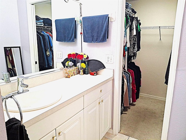 bathroom featuring a walk in closet, vanity, and baseboards