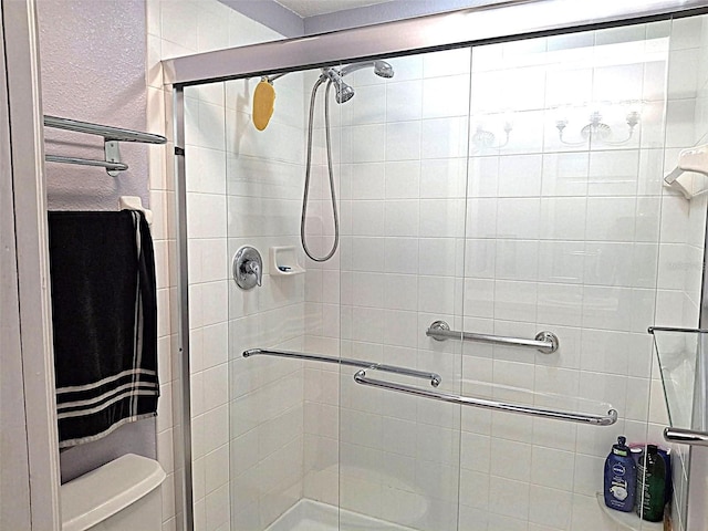 full bathroom with a textured wall, a shower stall, and toilet