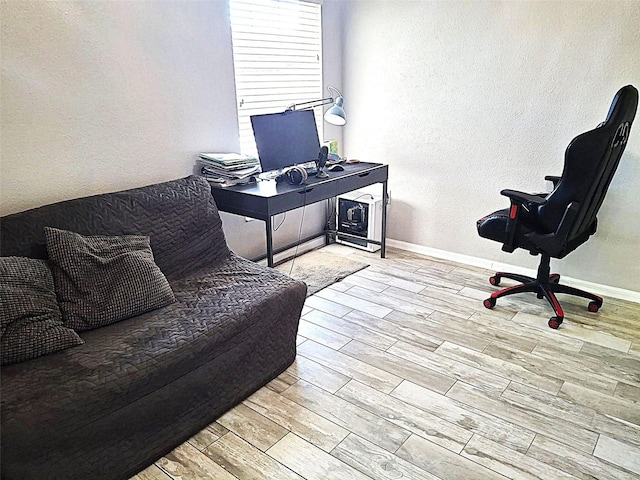 office space featuring a textured wall, baseboards, and wood finished floors